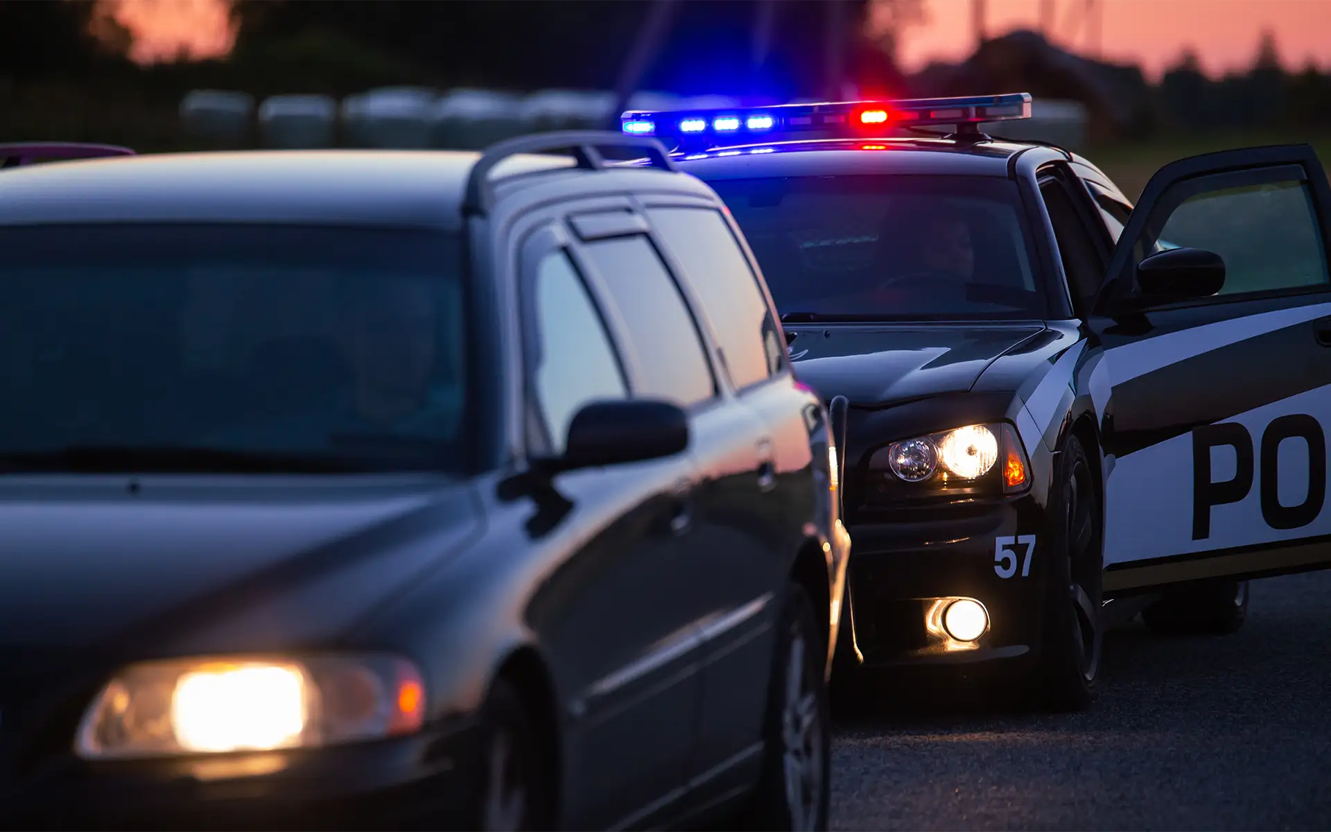 A car that is pulled over by the police for a traffic violation at dusk